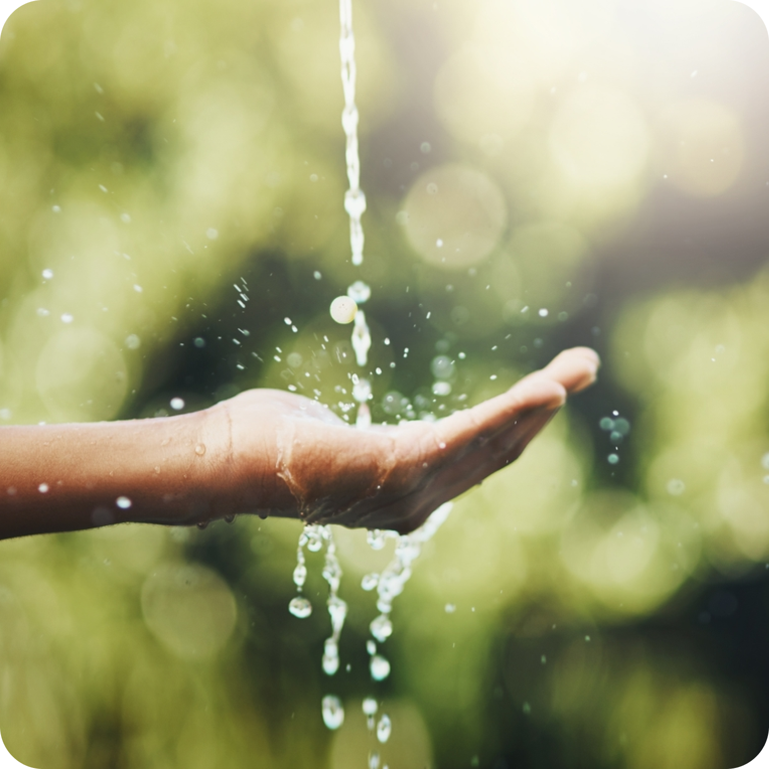 Hand catching streaming water outdoors, symbolizing hydration and natural electrolytes