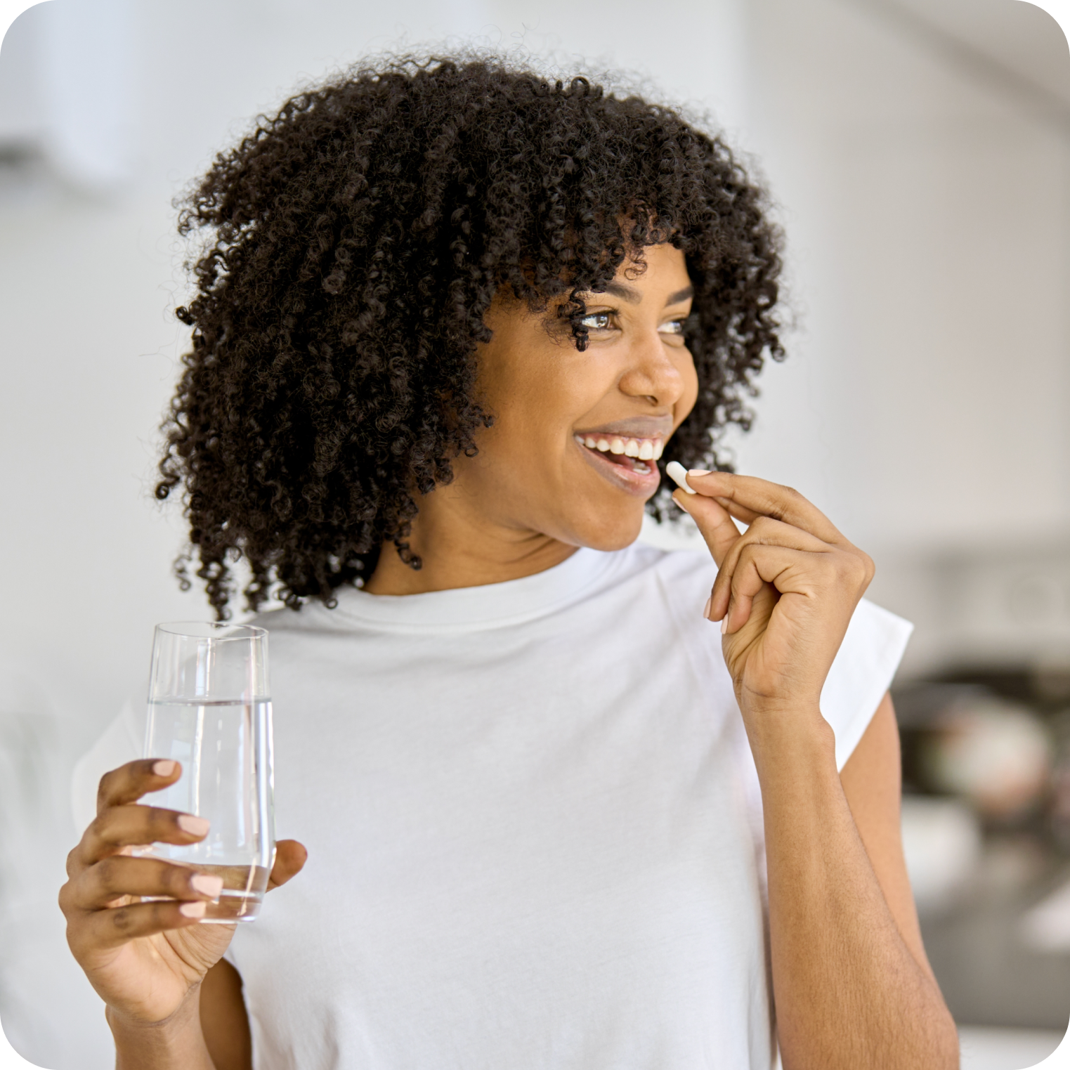 Woman holding a glass of water, preparing to take an electrolyte supplement tablet