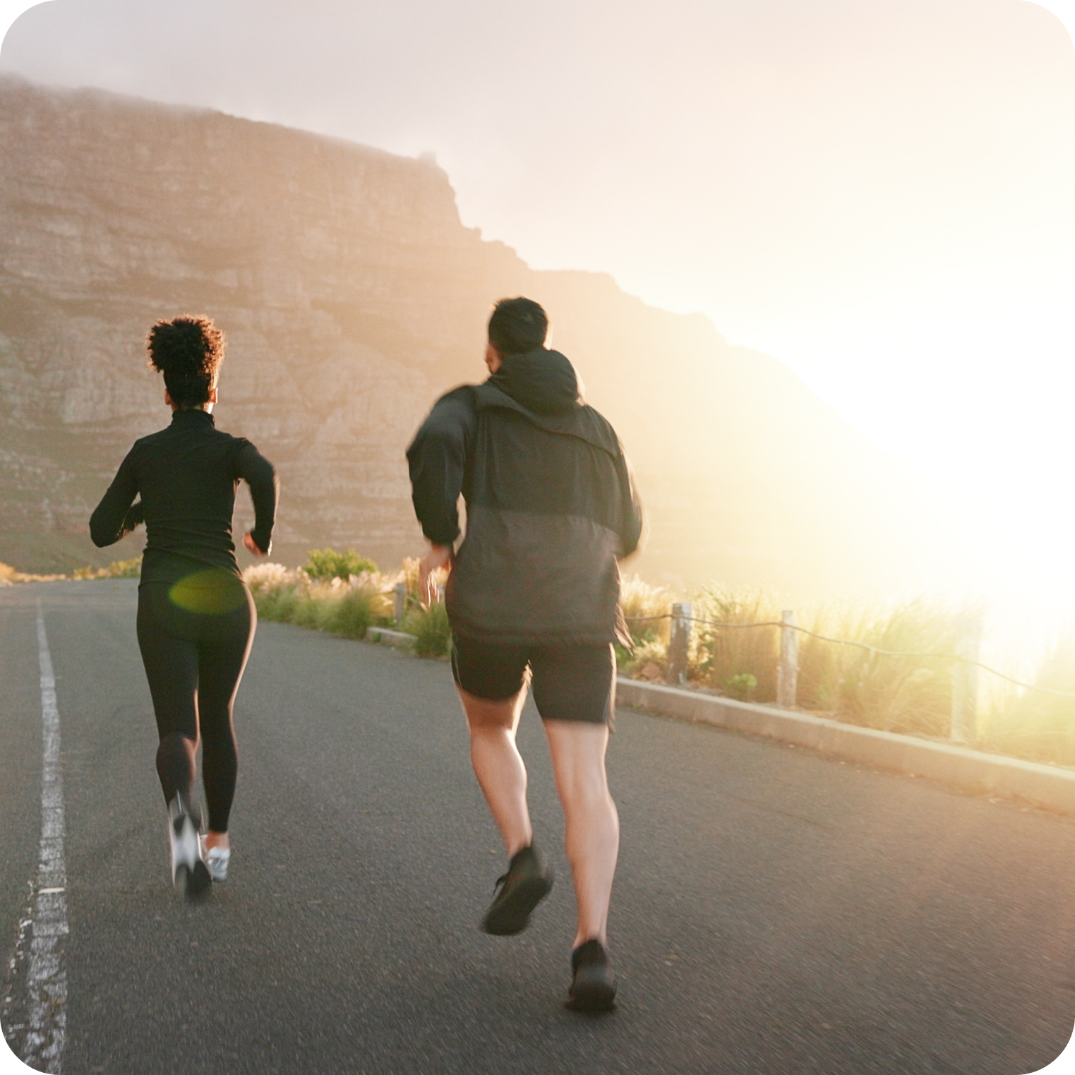 Two athletes running outdoors at sunrise with mountains in the background, promoting hydration.