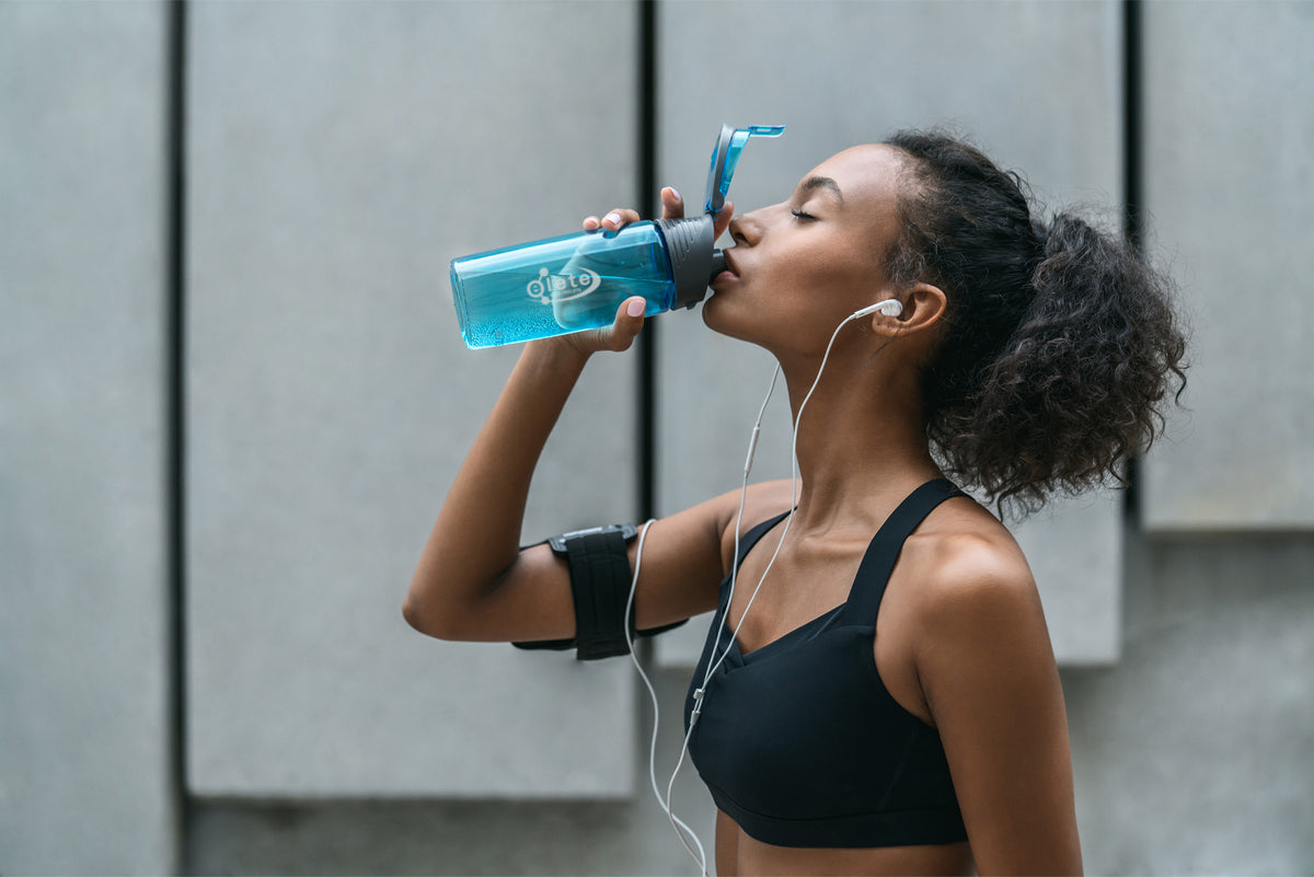 Woman drinking from a blue water bottle outdoors